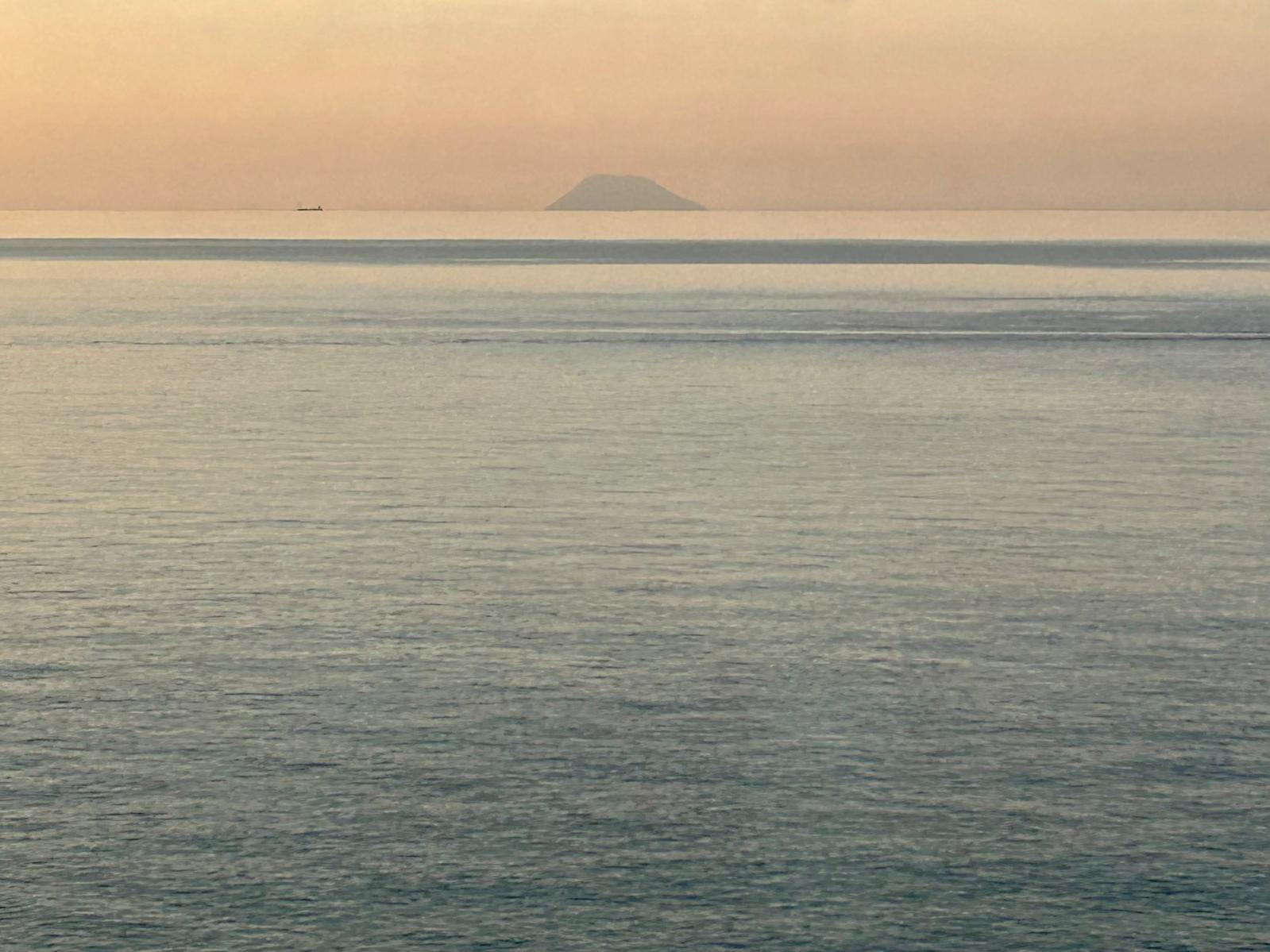 Sopka Stromboli viditelná z okna vlaku podél pobřeží